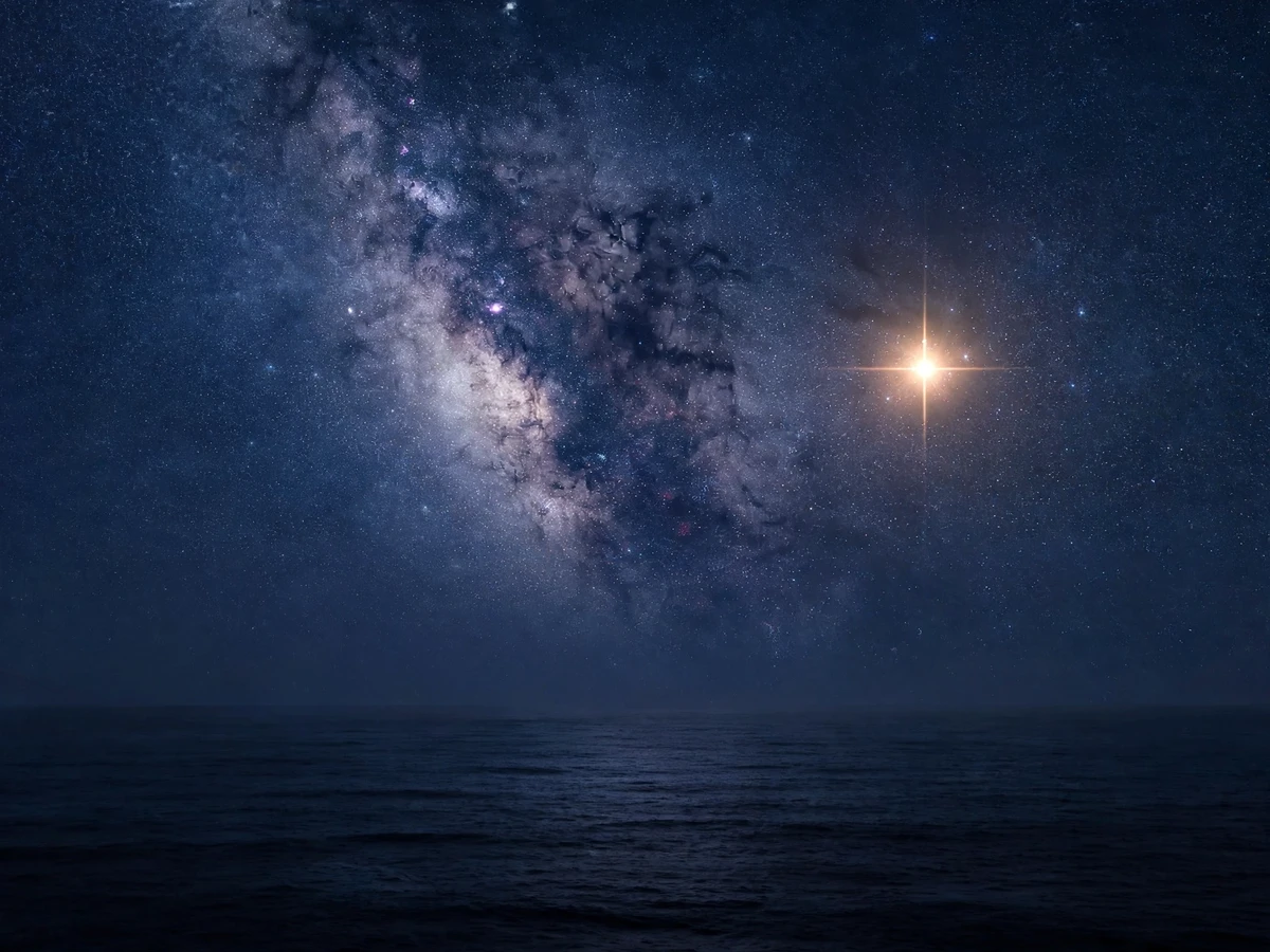 Bright stars scattered across a deep indigo night sky over the Pacific Ocean, the Milky Way visible